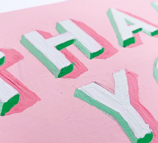 A zoomed-in view of hand-painted 3D block letters that say "Thank You" with green shaded sides and a bubblegum pink background